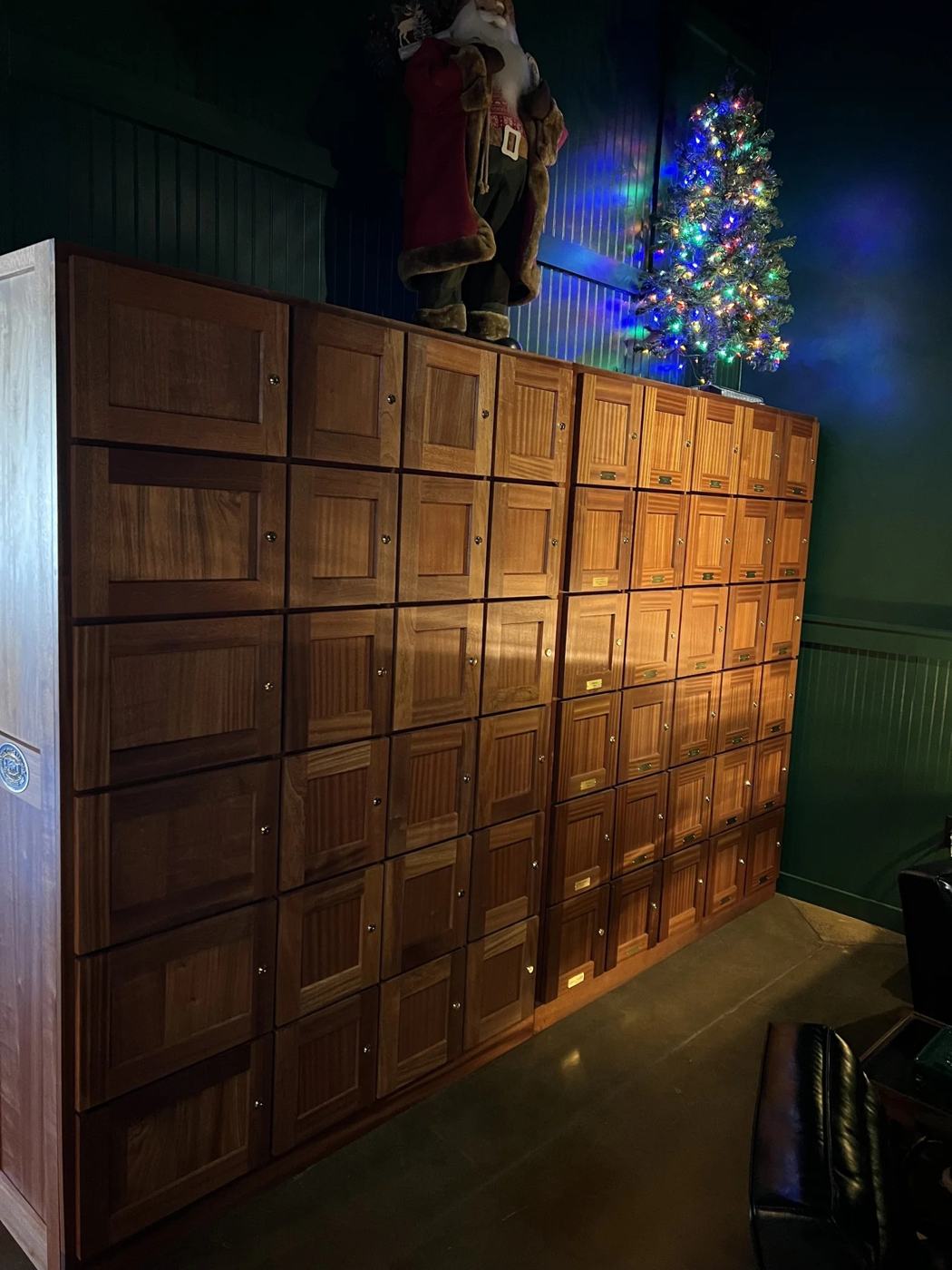 Wall of solid wood cigar lockers lit warmly in a lounge