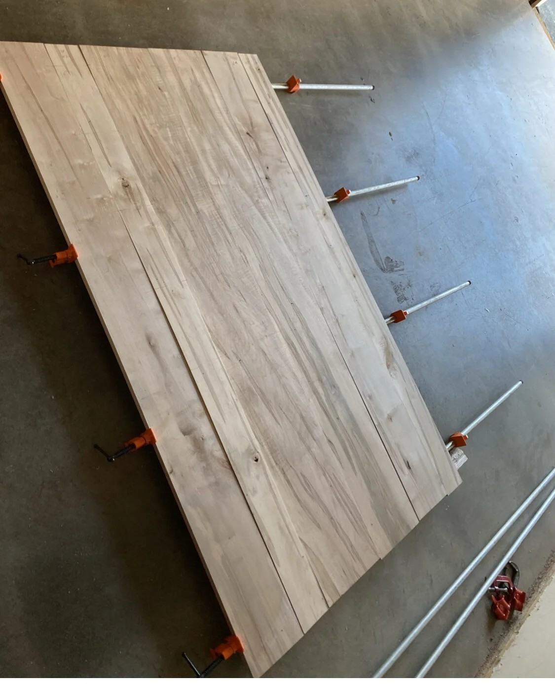 A tabletop glue-up held in a row of bar clamps