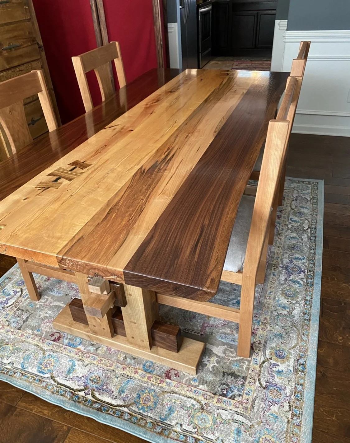 Walnut and maple slab dining table with butterfly keys and a matching bench, set in a dining room