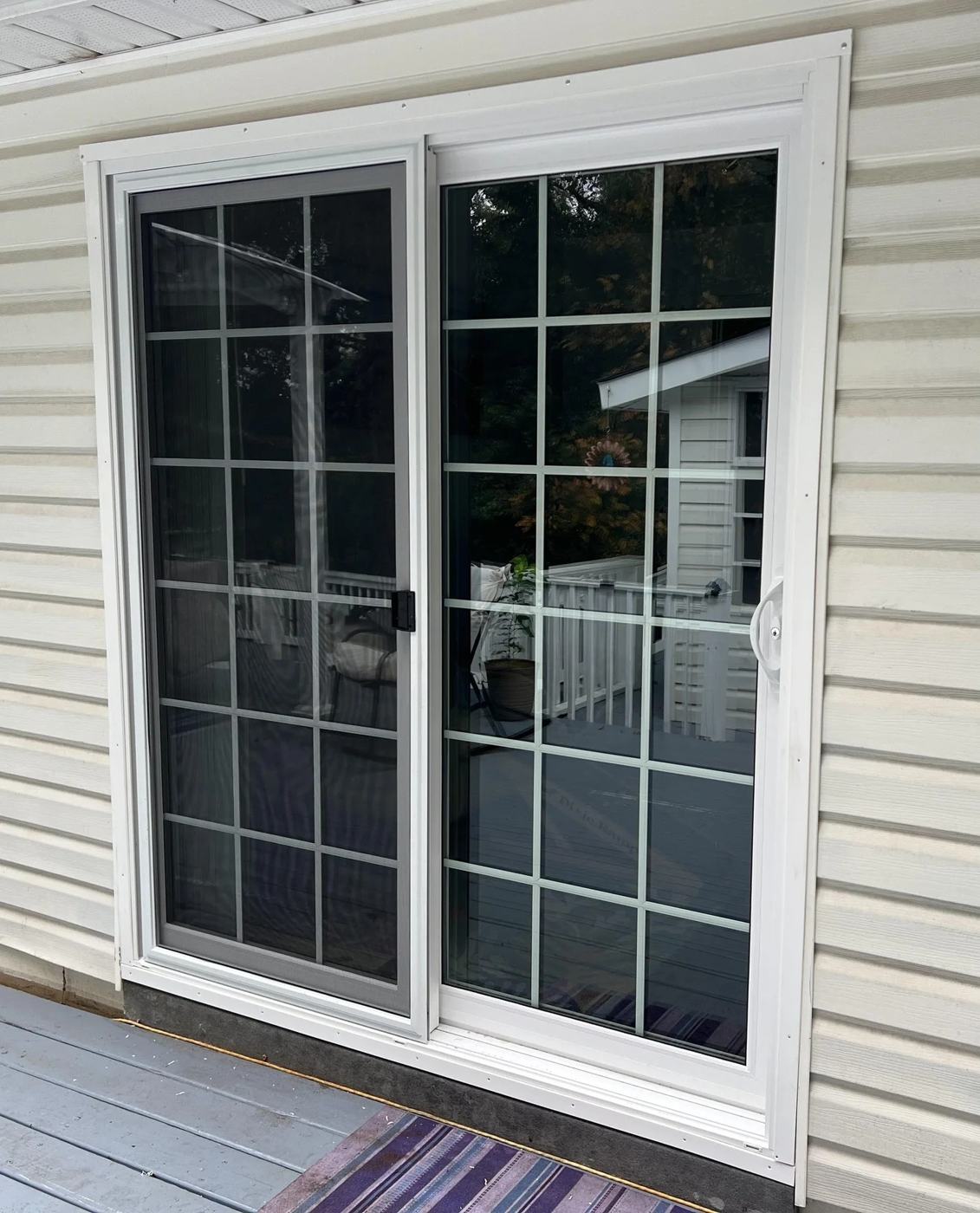 New white sliding patio door with grilles installed in vinyl siding