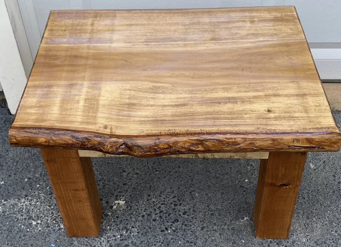 Thick live edge slab with rough edges set on square legs in the shop