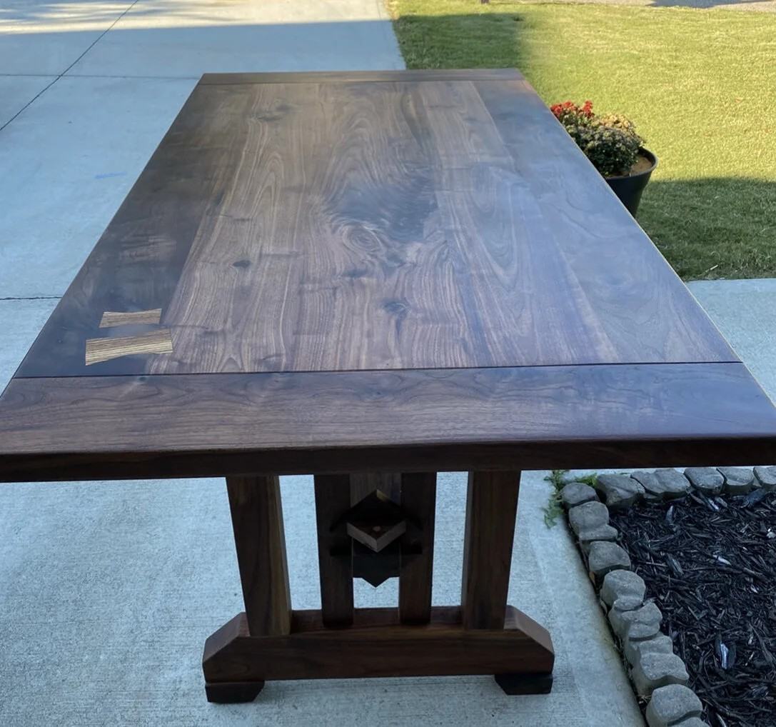 Solid walnut trestle table with contrasting butterfly keys, photographed outdoors